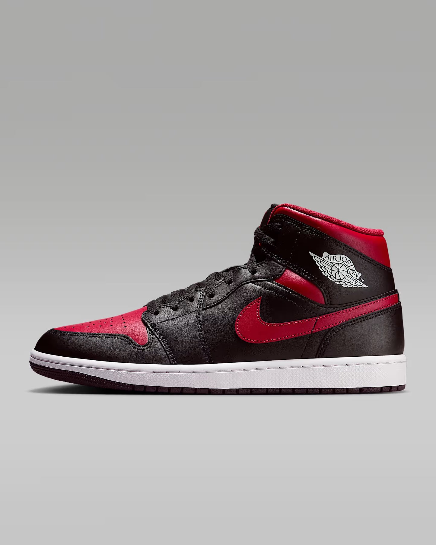 A pair of red and black Jordan 1 Mid sneakers