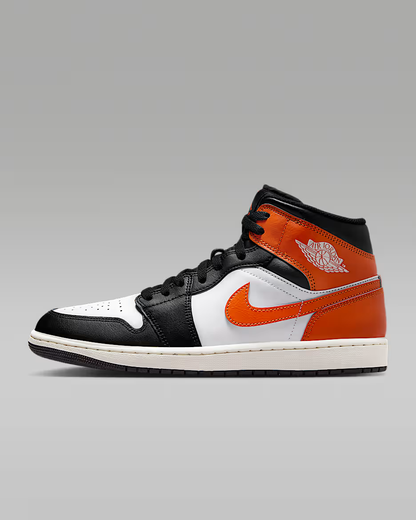 Black, orange, and white sneaker on a gray background